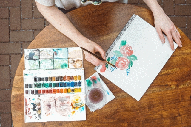 A mom uses watercolors to paint flowers with her family