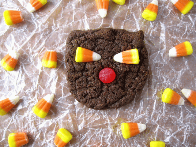 A black cat cookie with candy corn eyes