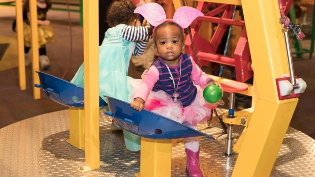 a little girl in a bunny costume trick or treats at childrens museum atlanta during a halloween event in atlanta