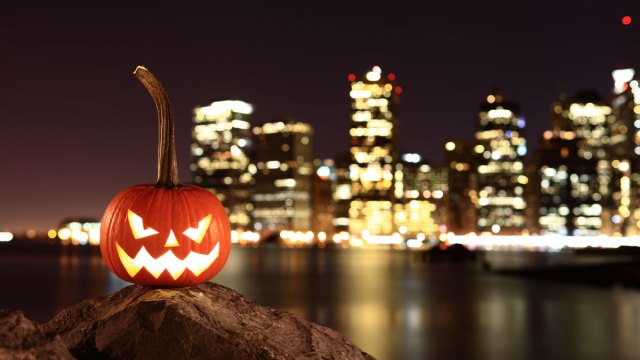jack-o-lantern pumpkin in front of Manhattan skyline at night