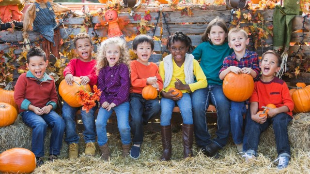 kids sit on hay bales in the fall with pumpkins for halloween events