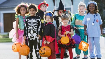 a group of kids in costumes is ready to go trick or treating with pumpkins in hand