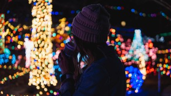 a person warms themselves with a cup of hot cocoa while out to see Boston Christmas lights