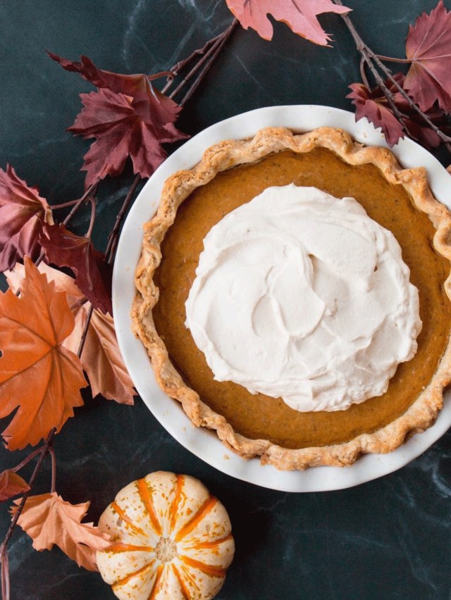 A full pumpkin pie topped with whipped cream as a Thanksgiving recipe from Little Sweet Baker