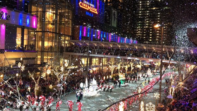 a parade goes down the street with snow falling in the background at Snowflake Lane in Bellevue, one of the best spots to see seattle christmas lights
