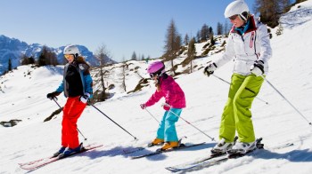 a family skis at a ski resort near portland during winter, snowy background with mountains