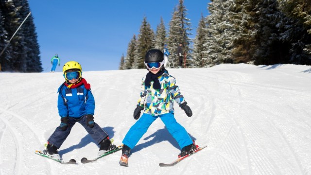 two kids ski down a mountain doing pizza wedges with trees in the background ski resorts near Portland