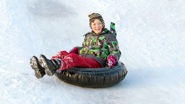a boy goes tubing near boston on a winter day with a black tube