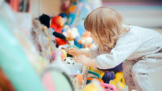 little girl looking through aisle of toys at toy store