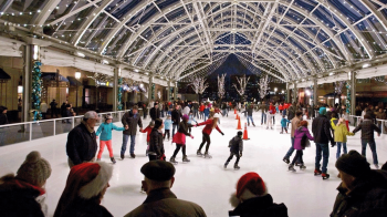 A covered ice skating rink in the DC area is filled with ice skaters and festive onlookers