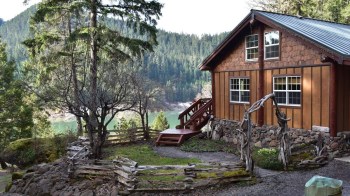 Cabins in portland oregon are often by a lake like this one that includes a rustic fence and old tree near the cozy wood cabin