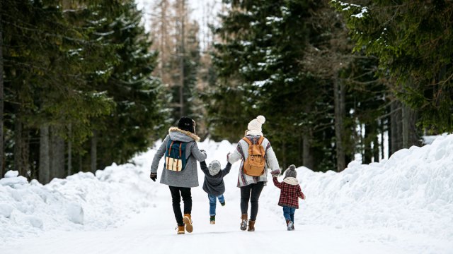 family walking along snowy path in nature forest