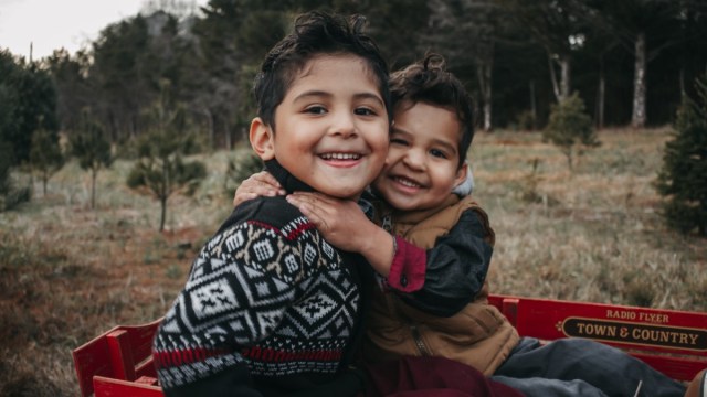 two boys hug each other in winter sweaters in wagon when looking for Christmas things to do in Portland