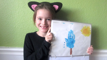 little girl showing off her handprint calendar