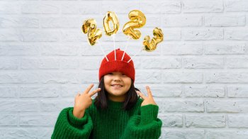 New Years eve Boston is going to be great for families--kid pointing to 2023 balloon wearing a red hat