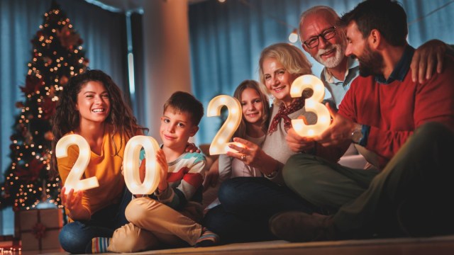 a family sits around with glowing 2023 numbers to celebrate new years eve