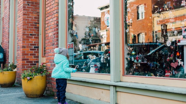 a young girl looks at a window in downtown bellingham, a winter getaway near seattle