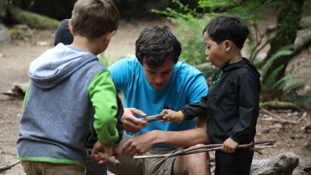 A boy gasps with delight as a camp counselor shows him something at a Seattle summer camps, wilderness awareness school