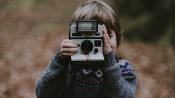 child holding polaroid camera
