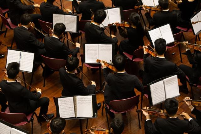Sheet music sits in front of musicians in an orchestra