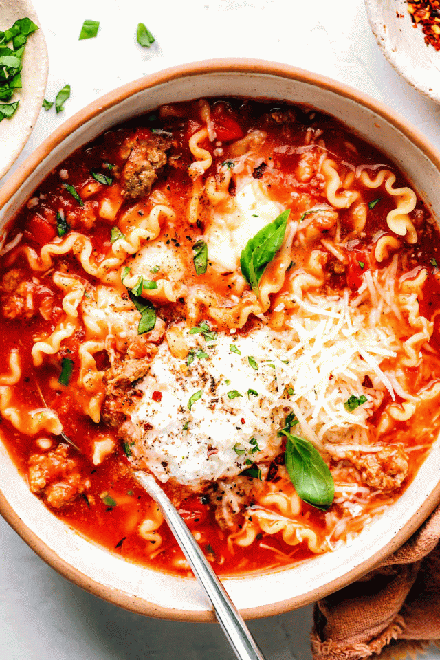 A bowl of freshly-cooked lasagna soup garnished with a few leaves of basil
