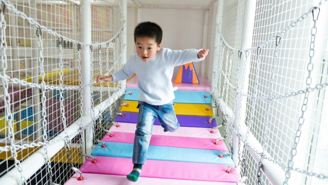 a boy runs on a bridge at an indoor playground things to do with kids
