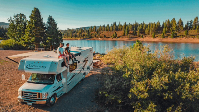 family camping on the side of a lake in an rv