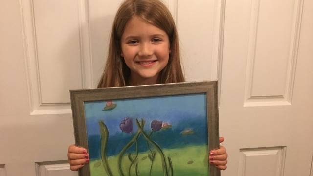 a girl holds a painting she made during things to do in bellevue with kids
