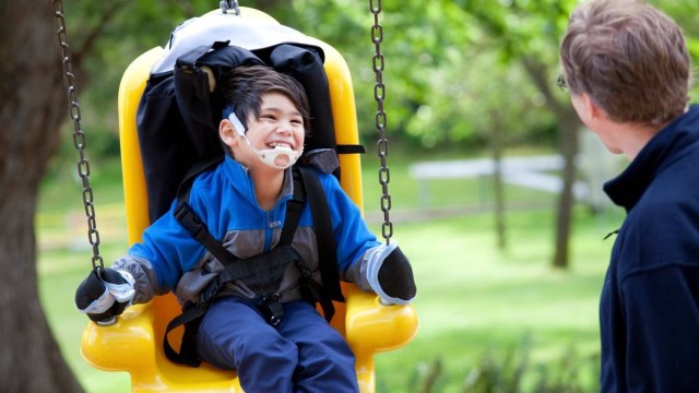 a kid swing in an adaptive swing on a playground