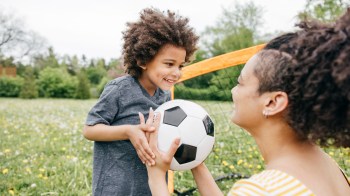 a little boy playing soccer with his mom for a story on children's astrology signs and their favorite activities