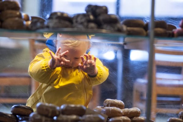 A toddler peeks at a case of donuts