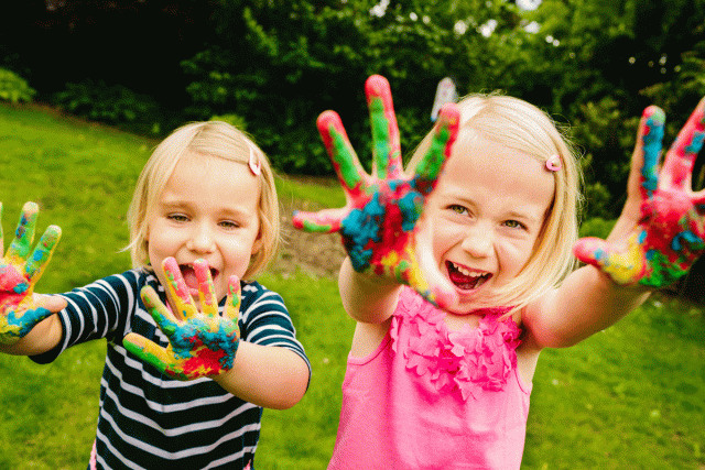 Two little girls show off their colorful hands at an art themed birthday party