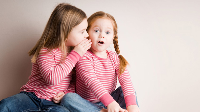 little girl telling her little sister an easy riddle