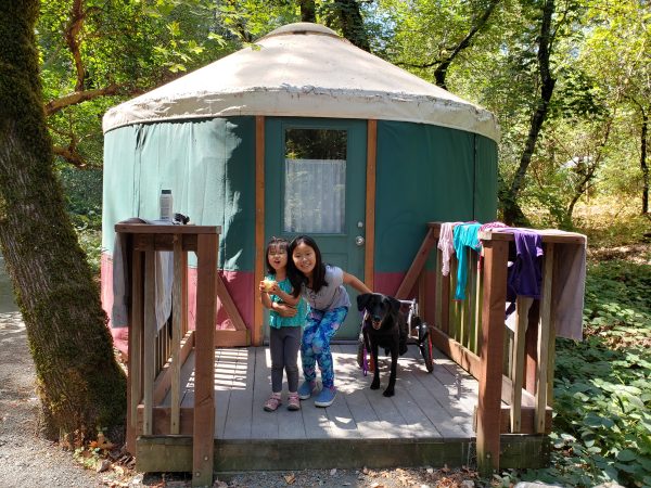 Two sisters stand outside a yurt in Napa Bothe State park with their dog