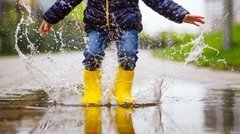a kid with yellow rainboots jumps in a puddle, a favorite things to do on a rainy day, rainy day activities with kids