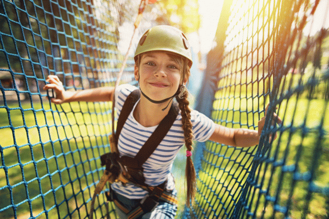 A girl in a helmet smiles as she gets ready to go ziplining