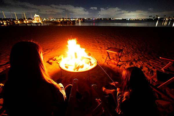 Two girls enjoy s'mores and a beachside bonfire