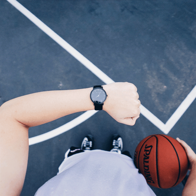 A boy looks at his watch while playing basktball