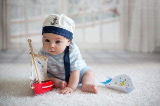 baby boy dressed in nautical outfit playing with boat