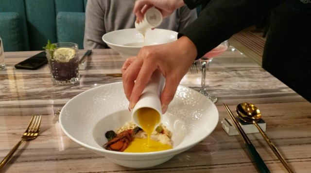 A waiter pours soup into a bowl