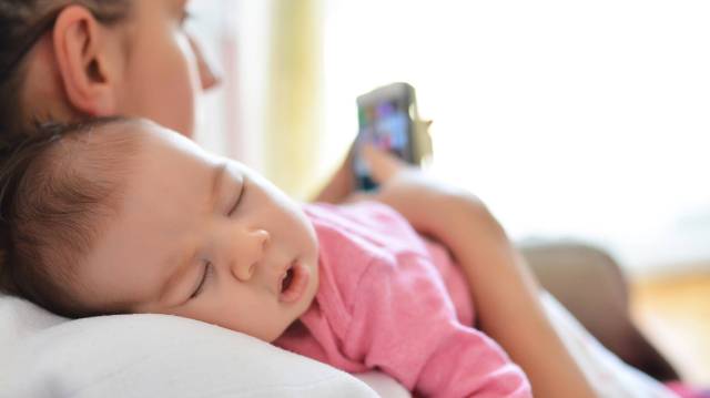 mother with sleeping baby checking phone