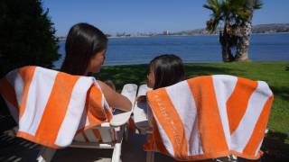 Two girls sit by the beach on adirondack chairs in on a family beach vacation in Mission Bay