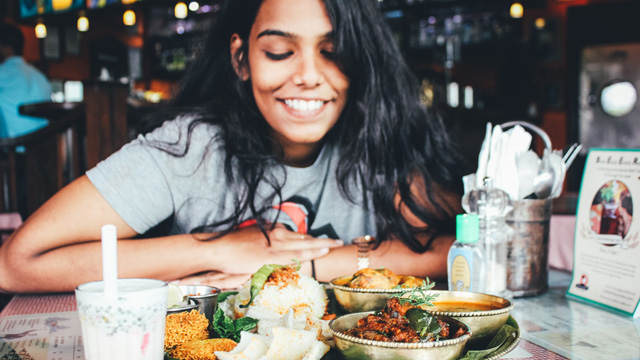 a woman eating Indian food