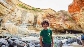 Oregon beach camping at its best, boy stands under Devils Punchbowl