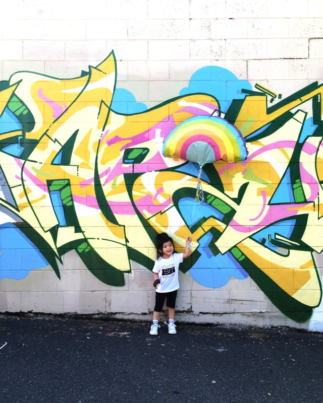 a stylish kid poses in front of wall murals in seattle