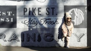 a child stands in front of a wall murals in seattle near Pike Place Market