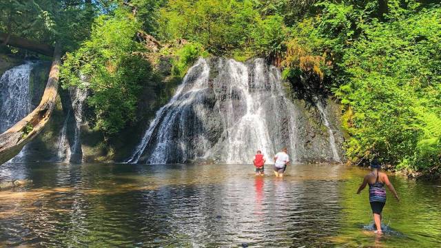 Kids wade into the pool below cherry creek falls a seattle waterfall hikes