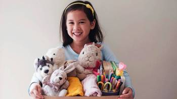 A girl holds a box of toys to donate