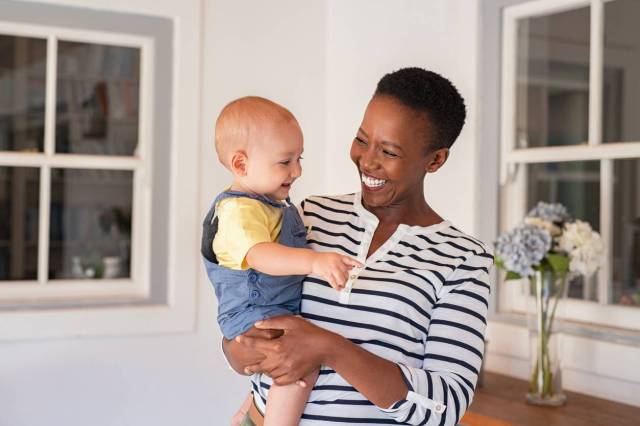 smiling Black woman mom with white baby - money-saving tips