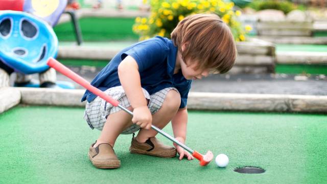 a boy peers into the hole at one of Seattle's best mini golf courses